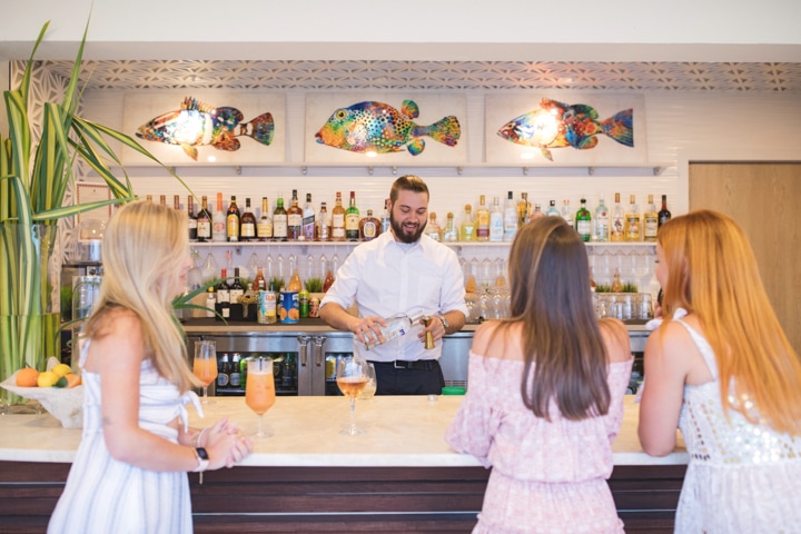 A bartender serving drinks to three people.