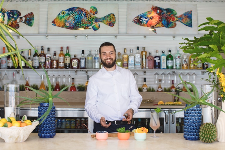 A bartender standing behind a bar, smiling.
