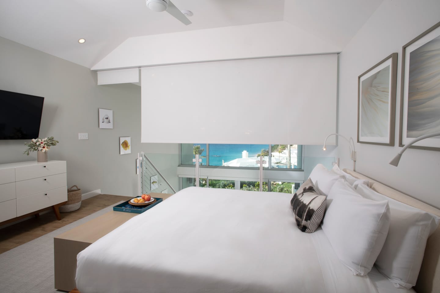 A loft bedroom with white shades covering a large window.