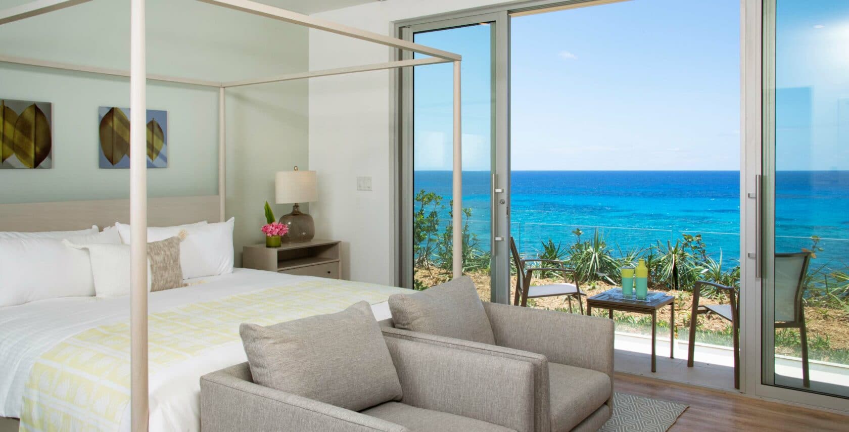 A bedroom with large sliding glass doors leading to a patio overlooking the ocean.
