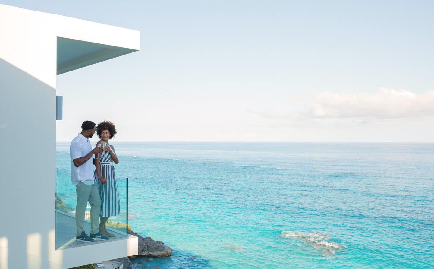 A couple on a balcony overlooking the ocean.
