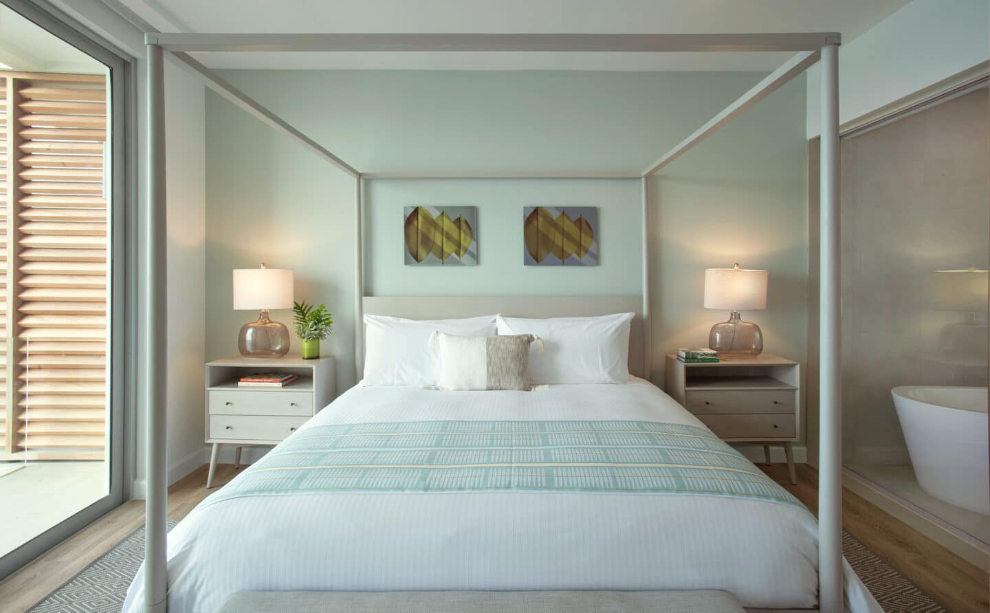 A canopy bed with white sheets and pillows.