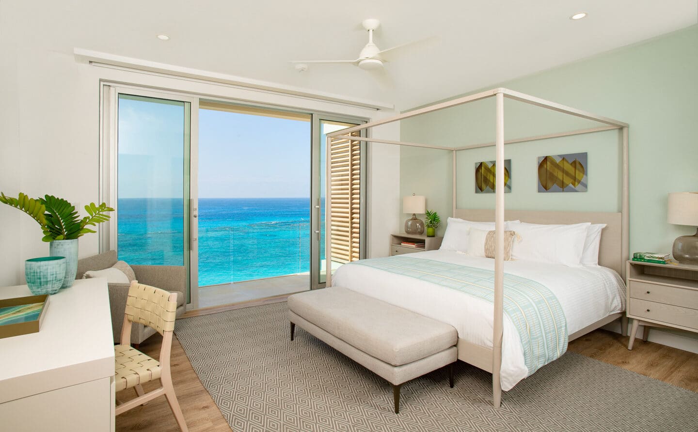 A bedroom with large glass doors with an oceanfront view.