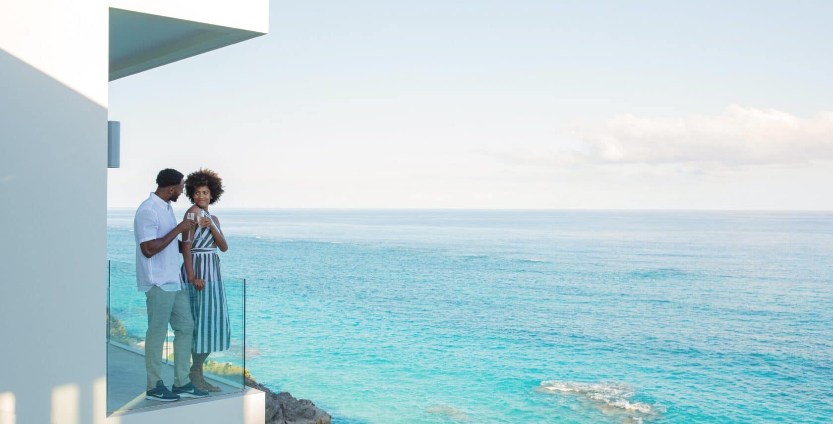 A couple on a balcony overlooking the ocean.