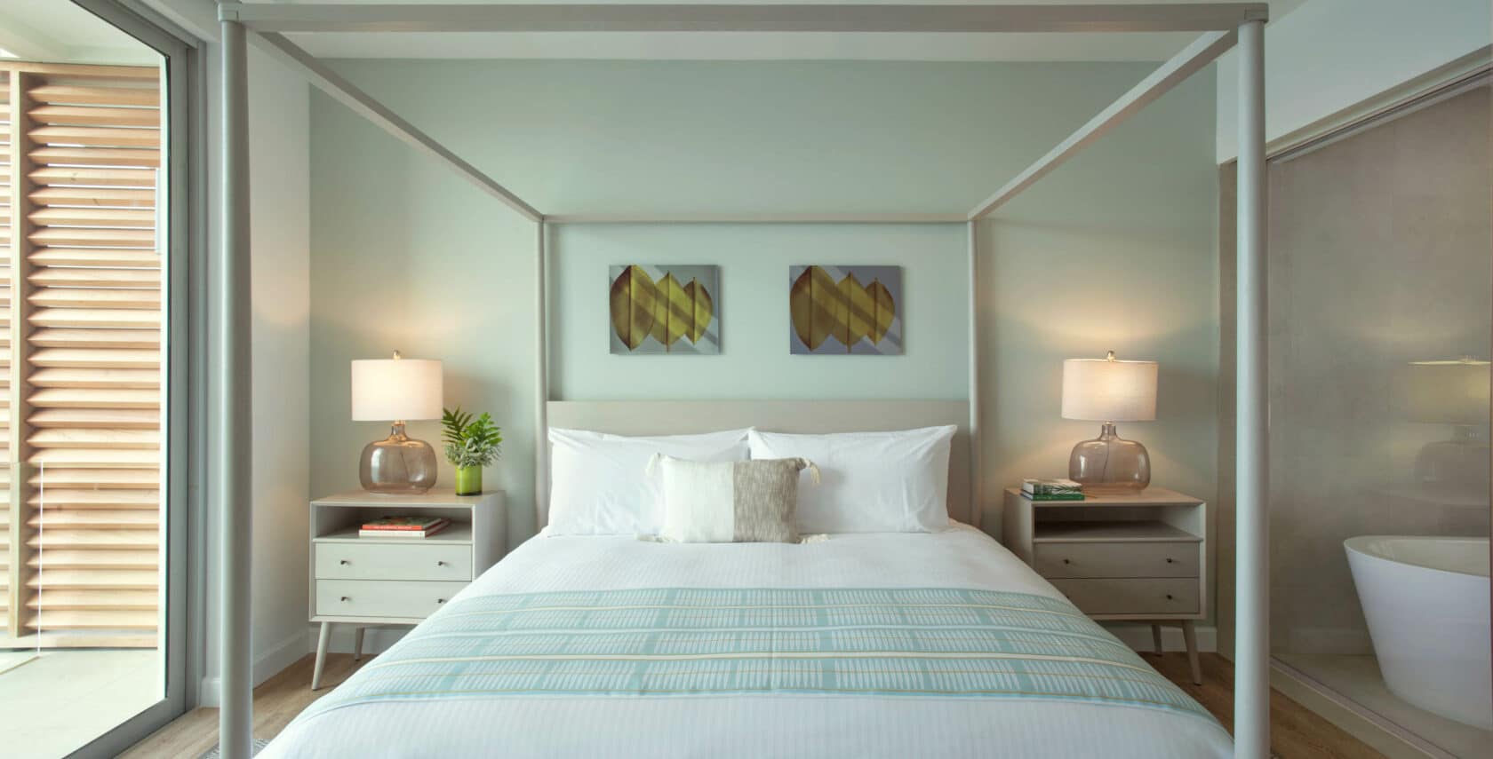 A canopy bed with white sheets and pillows.