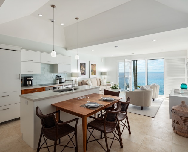 A kitchen and dining area with a living area in the background.