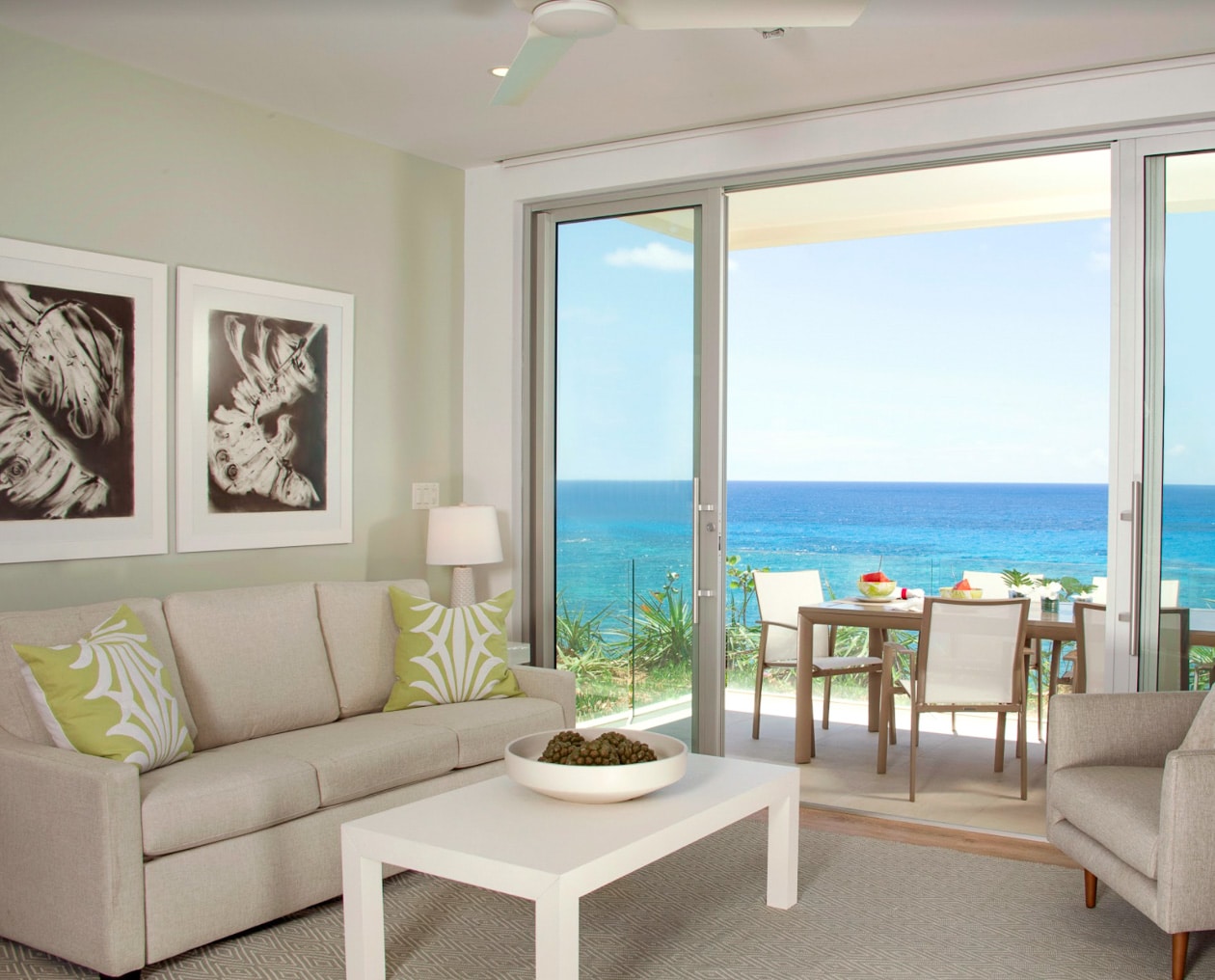 A living area with large glass doors leading to an outdoor dining area with an ocean view.