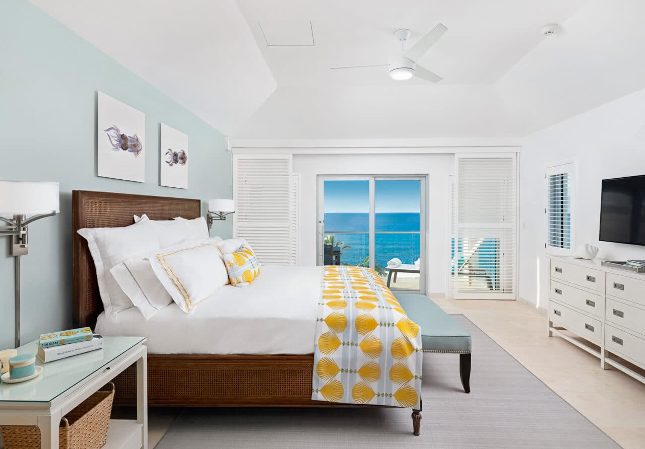 A bedroom with glass doors showing an ocean view.