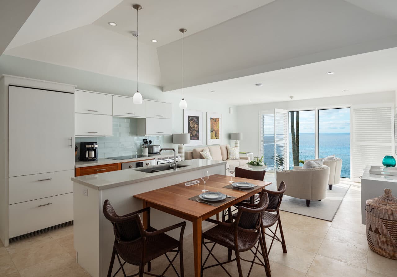 A kitchen area with white cabinets and a brown dining table.