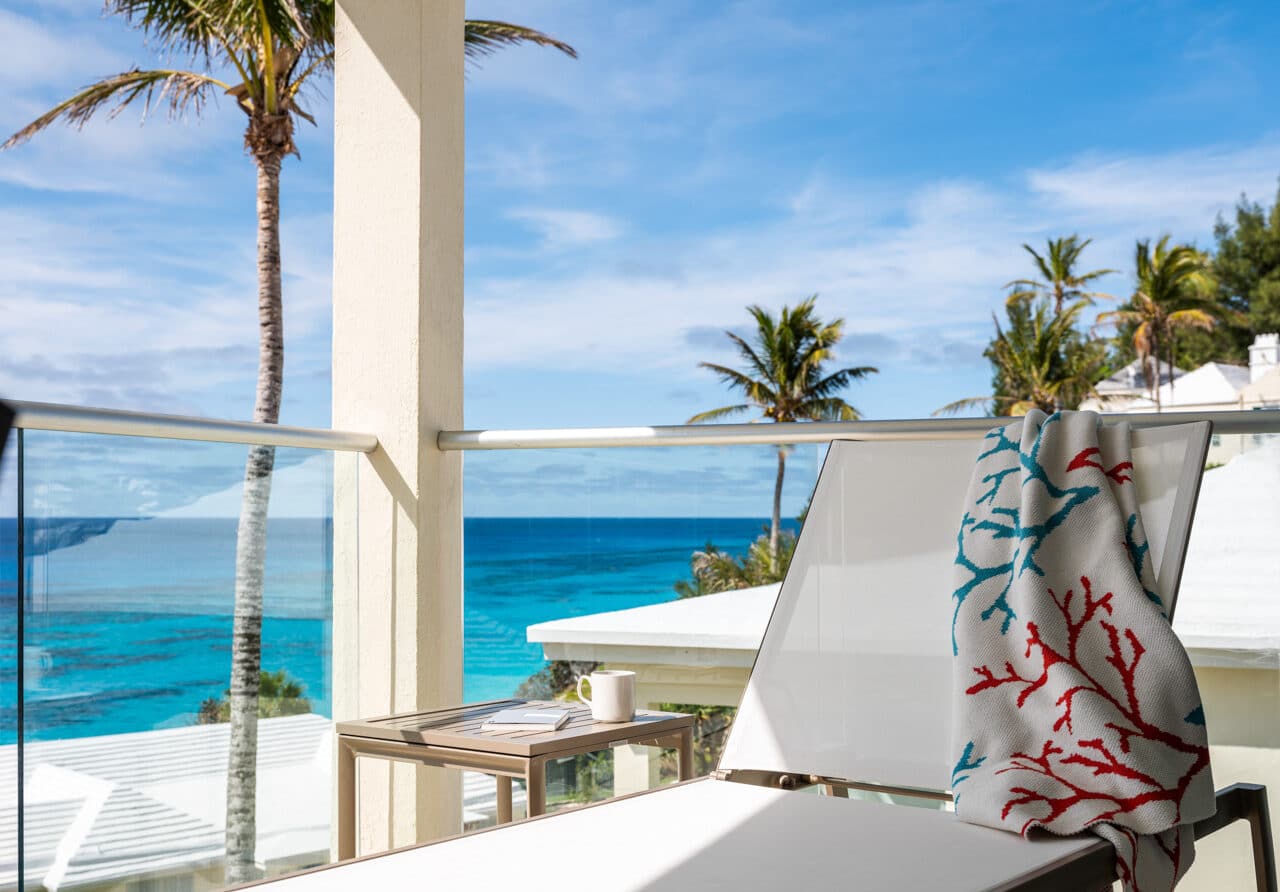 A lounge chair with a towel draped over it, with an ocean view in the background.