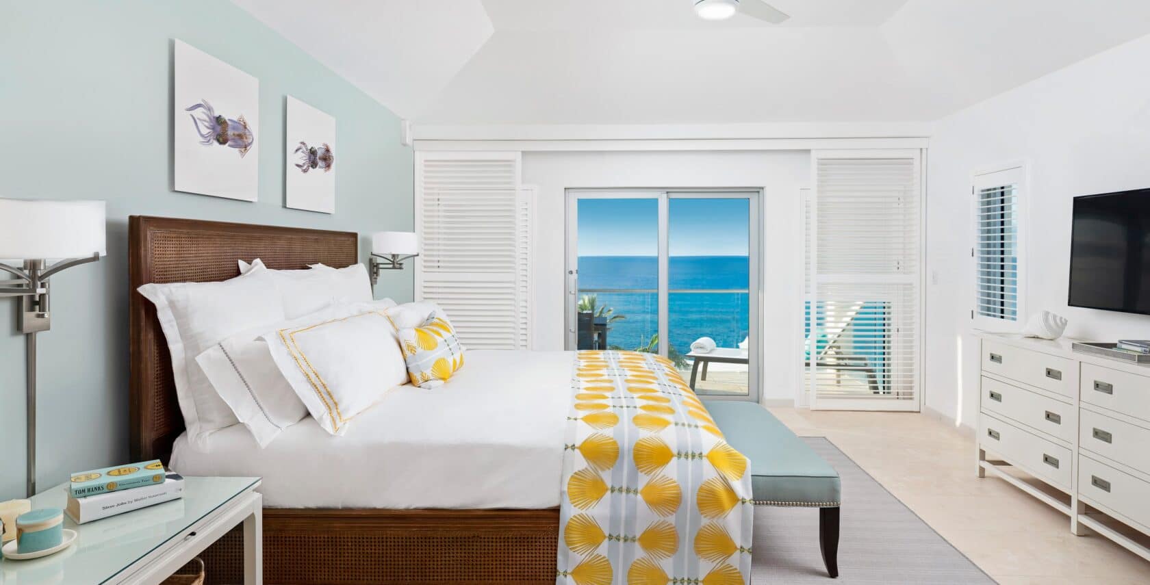 A bedroom with glass doors showing an ocean view.
