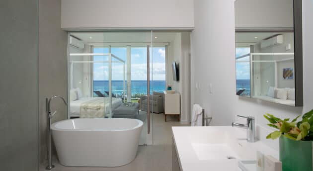 A bathroom connected to a bedroom with a sliding glass door in between.