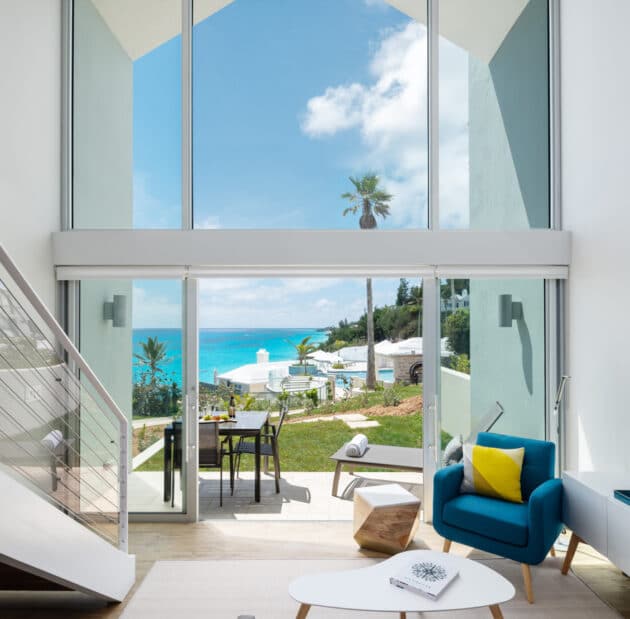 A living room area with a tall ceiling and sliding glass doors leading to a patio.
