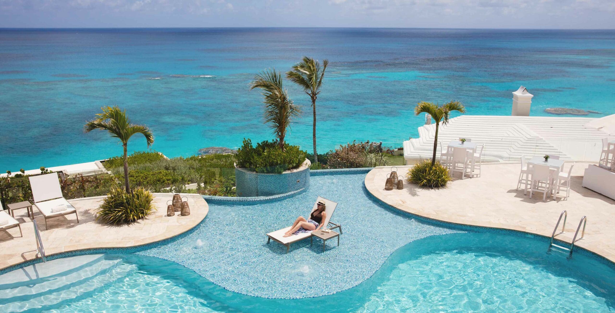 A person relaxing at an outdoor pool overlooking the ocean.