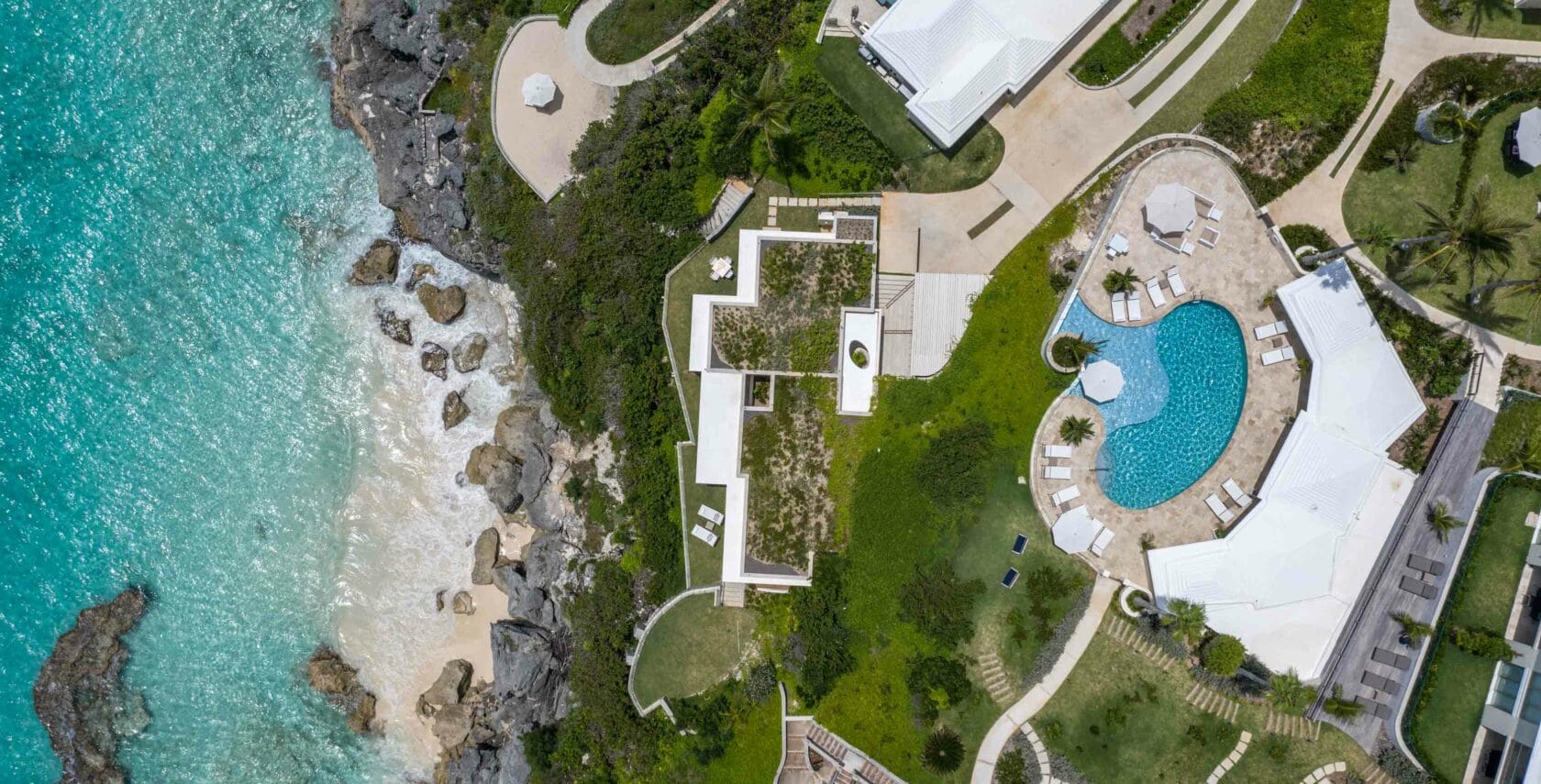 An aerial view of a house, pool, cliffs, and a beach.