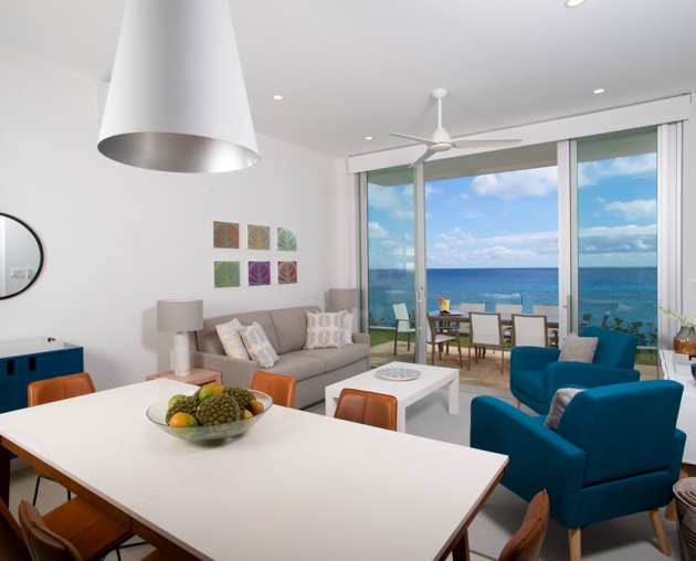 A dining table and a living area with couches, along with sliding glass door leading to an outdoor dining area.