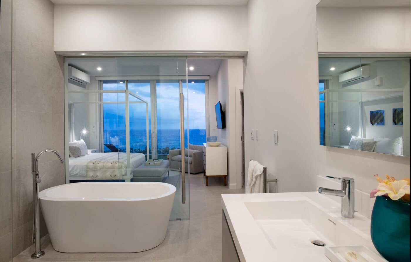 A bathroom connected to a bedroom with large glass doors.