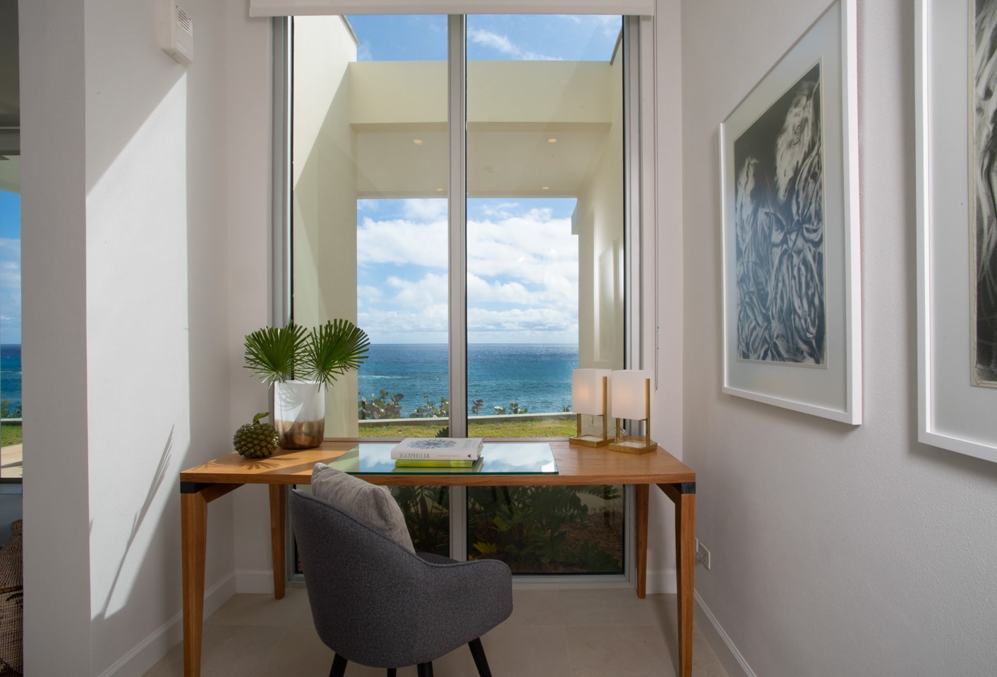 A desk in front of tall windows showing an ocean view.