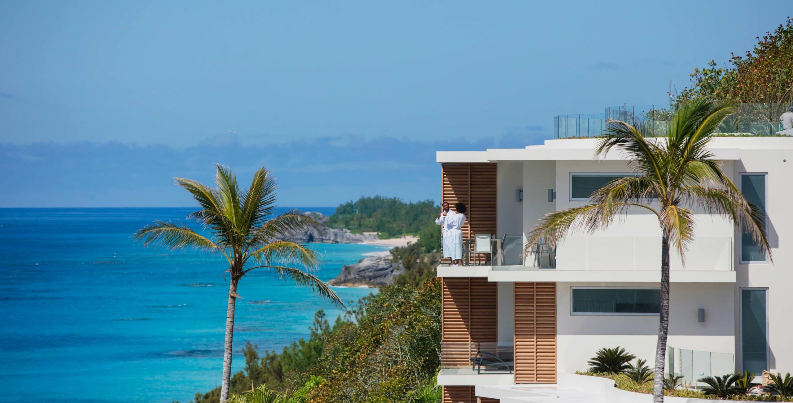 A couple on a balcony of a resort overlooking the ocean.