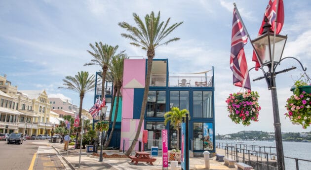 A street on the waterfront with colorful buildings and palm trees.