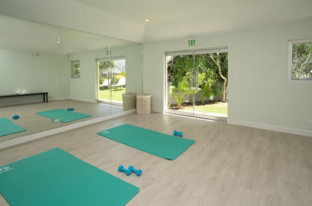 A yoga studio with a large mirror and two mats on the floor.