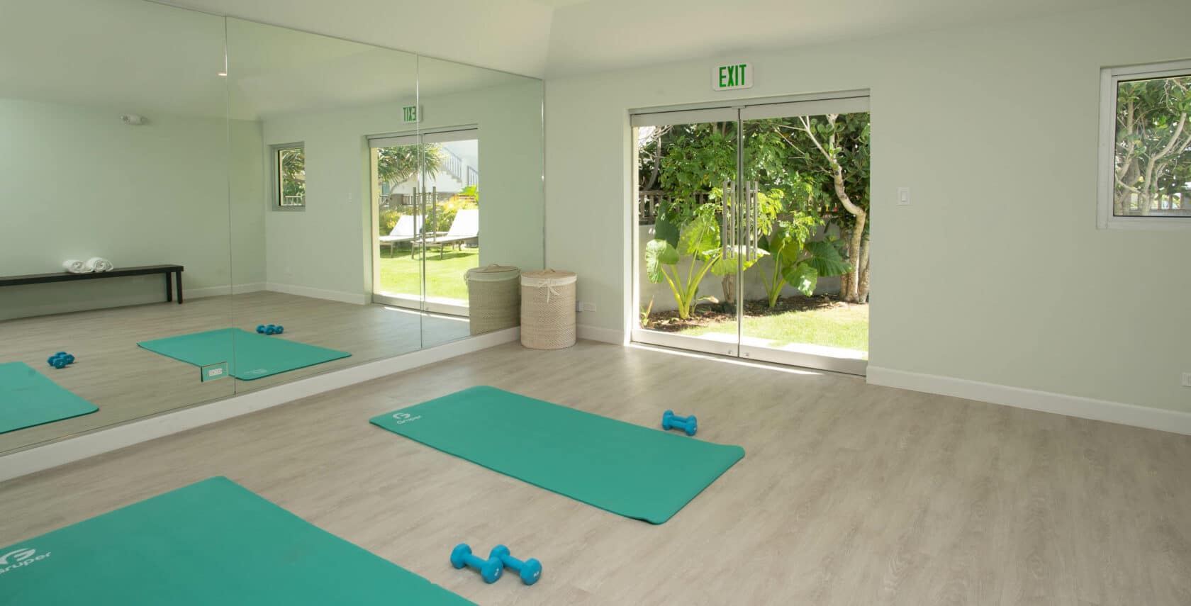 A yoga studio with a large mirror and two mats on the floor.