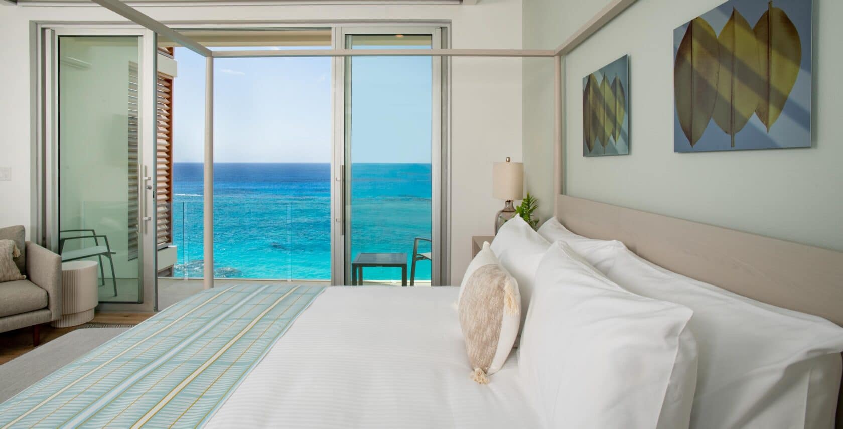 A bedroom with large glass doors with an oceanfront view.