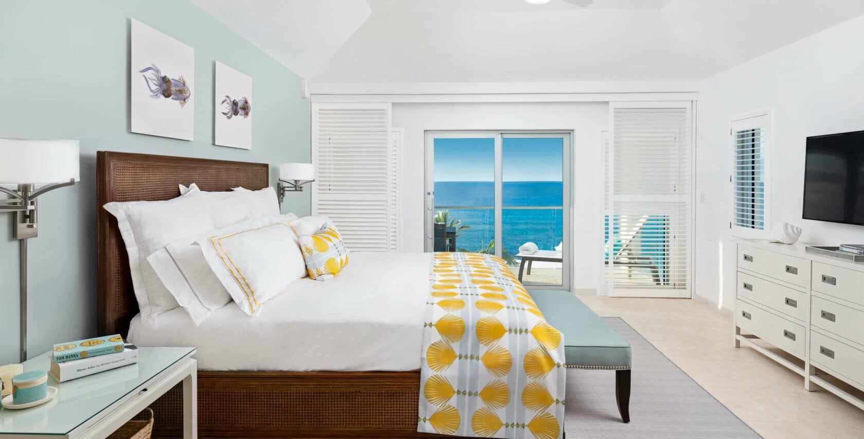 A bedroom with large glass doors showing a view of the ocean.