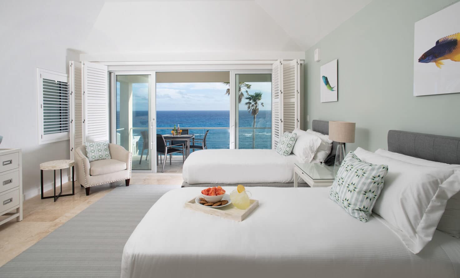 A bedroom with two beds and sliding glass doors with an ocean view.