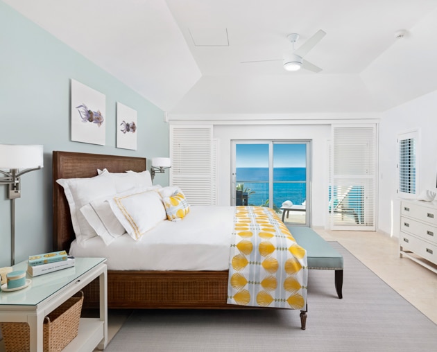 A bedroom with large glass doors showing a view of the ocean.