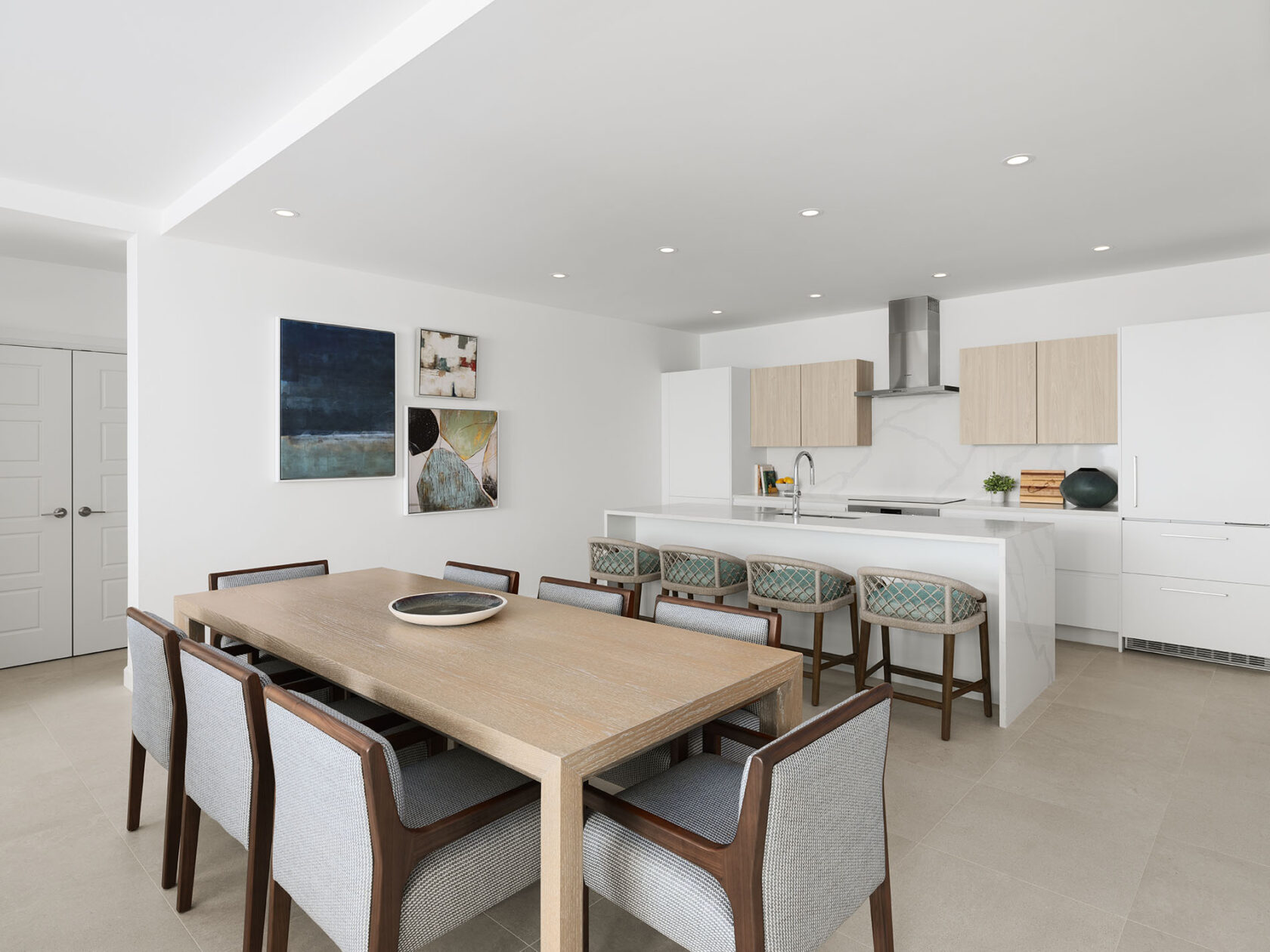 Modern open-concept kitchen and dining area with a wooden table, eight chairs, white cabinets, an island with bar stools, and contemporary artwork on the walls reminiscent of luxury hotel Bermuda aesthetics.